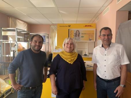 Ortsbürgermeister Tobias Rohrwick (links) und VG-Bürgermeister Ralph Bothe (rechts) freuen sich mit Alexandra Baas über die Eröffnung der neuen Postfiliale in Flörsheim-Dalsheim.